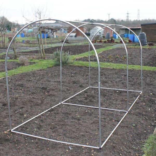 An aluminium hoop frame structure set up on a garden plot, designed for protecting fruit bushes, trees, or vegetables.