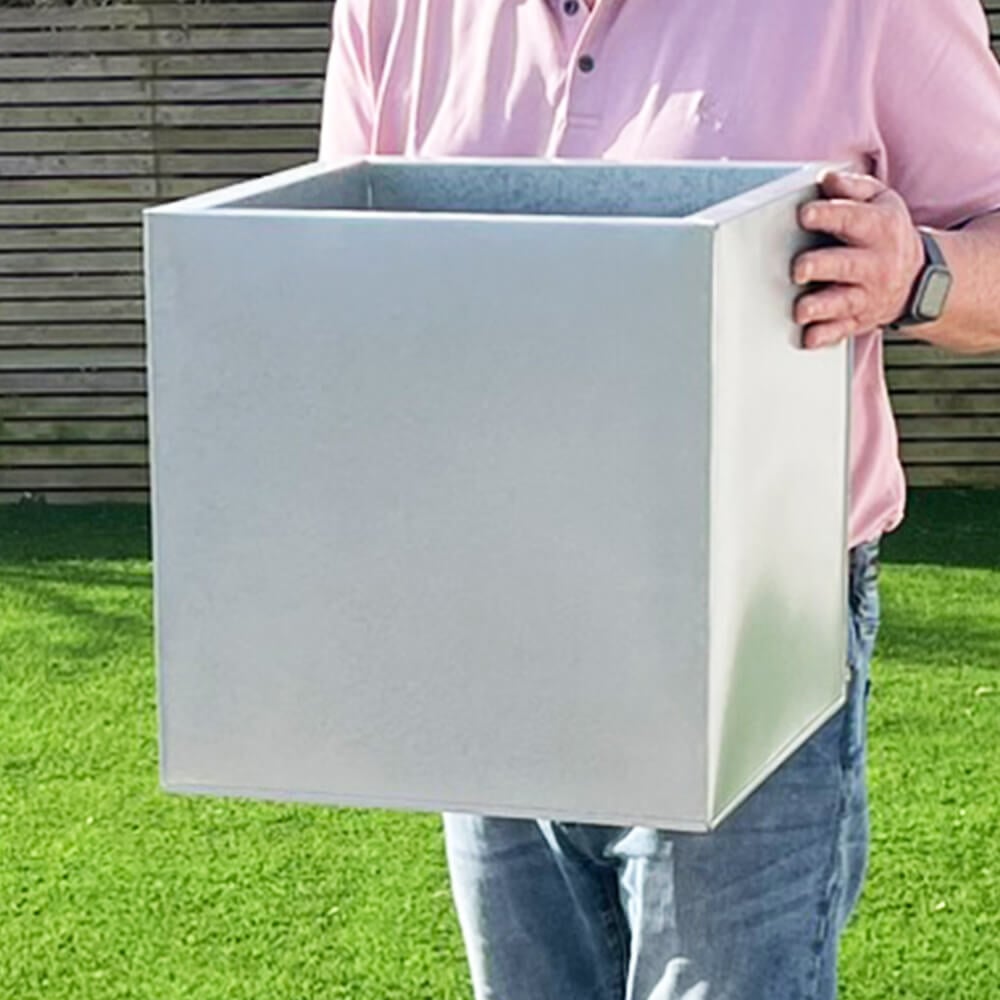 Three silver cube-shaped zinc planters in different sizes, with the smallest in front, medium in the middle, and largest in the back, placed on a patio with plants inside them.