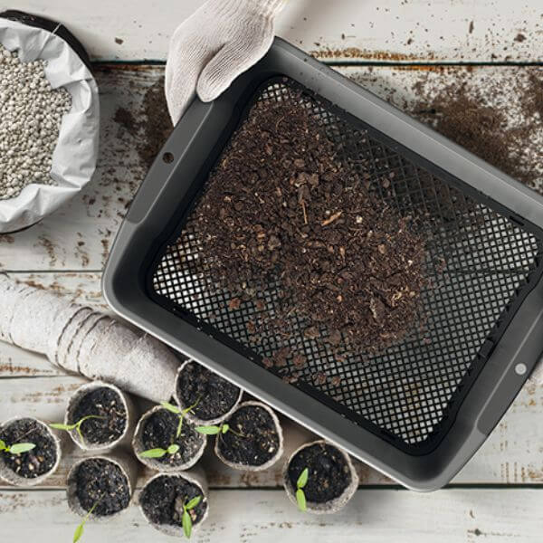 soil sieve on a potting table with plants in pots.