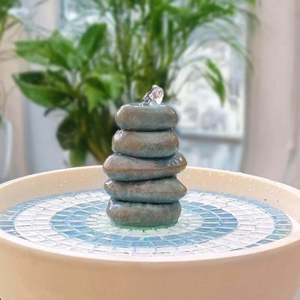 Small stone fountain on a decorative table with plants