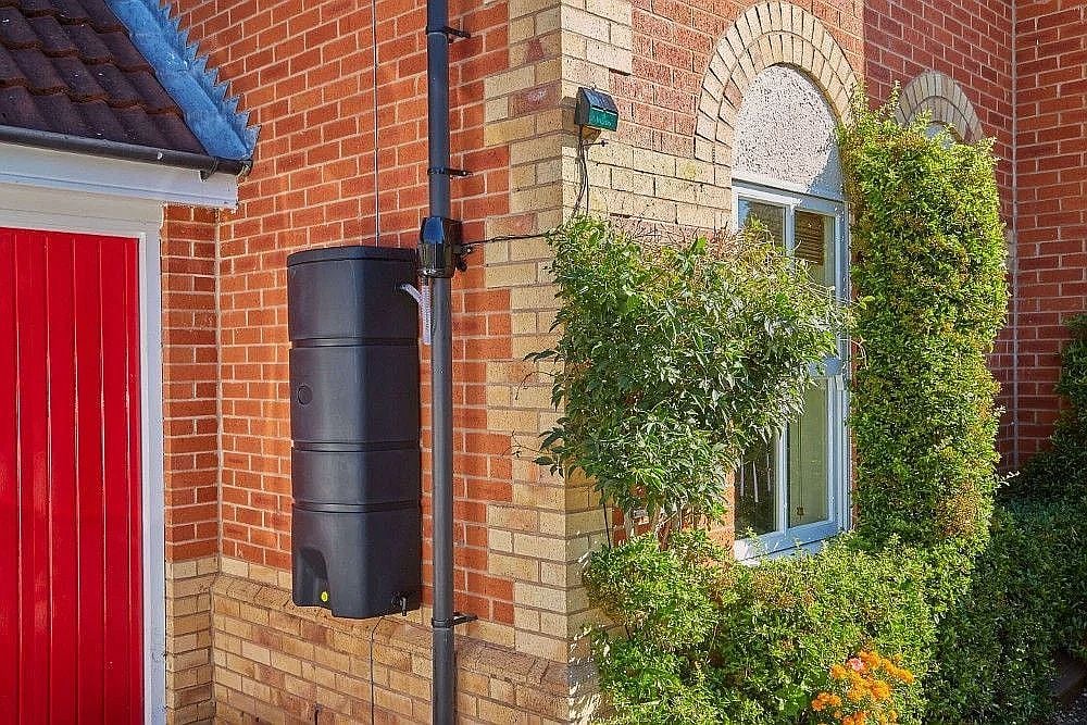 Wall mounted waterbutt on side of red bricked house