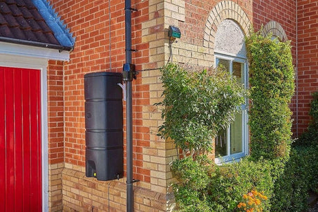Wall mounted waterbutt on side of red bricked house