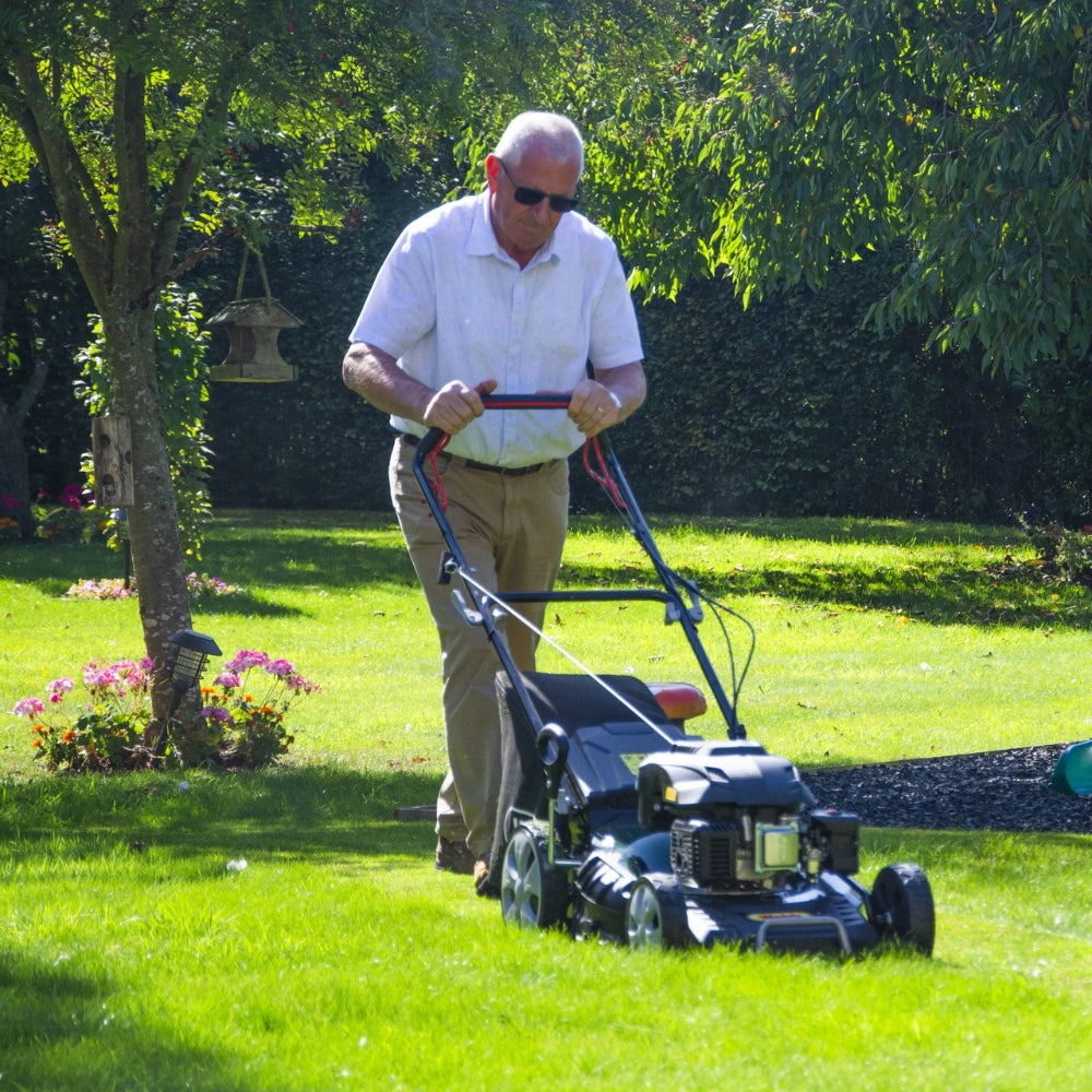 petrol lawnmower in use in garden