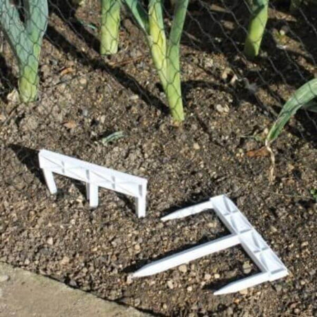 Three white, three-pronged pegs driven into the ground