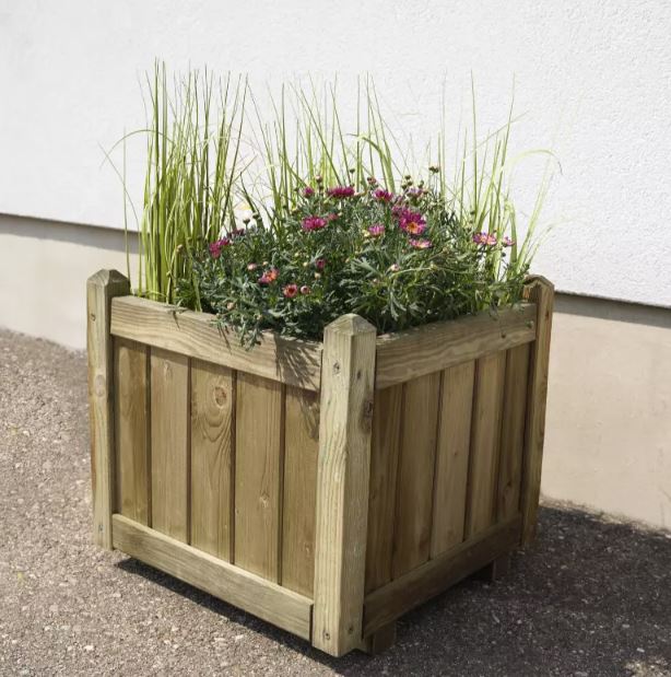 Wooden planter box with plants against a white wall