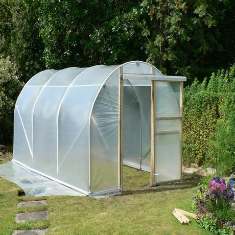 Polycarbonate greenhouse in a garden setting with greenery