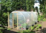Polycarbonate greenhouse with plants in a garden setting