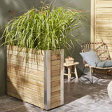 Wooden planter with green plants in an outdoor setting with a chair and table.