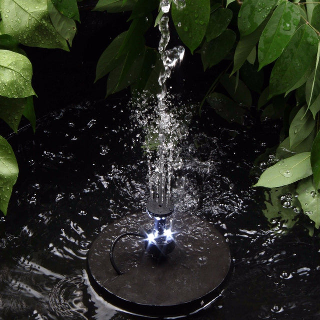 Solar fountain in pond surrounded with plants