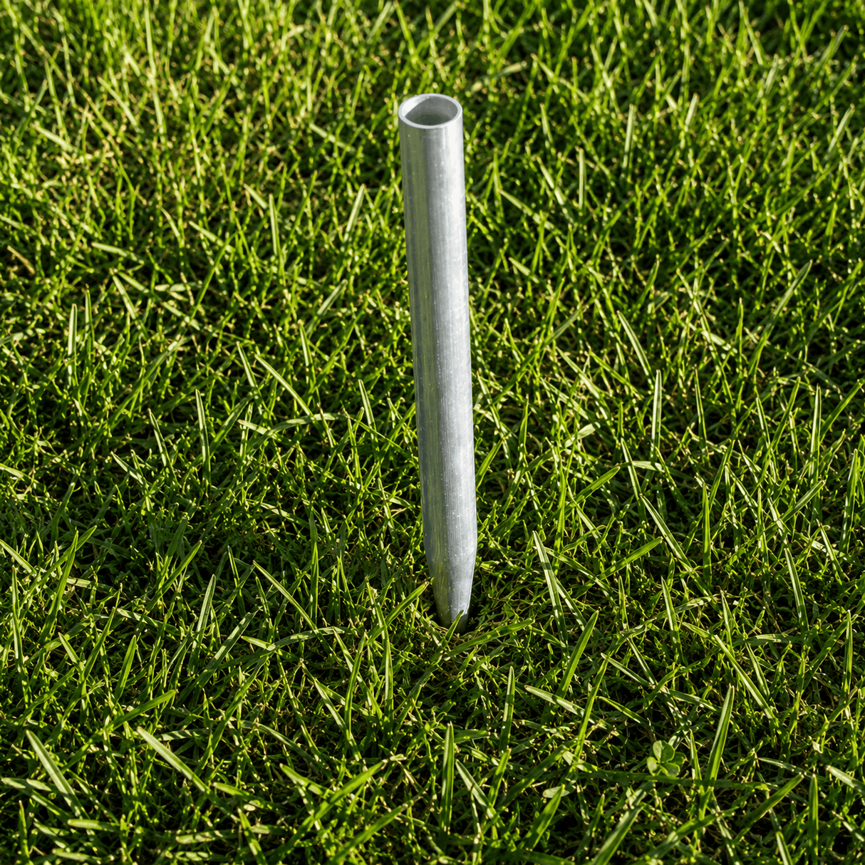 Metal pipe standing upright in green grass
