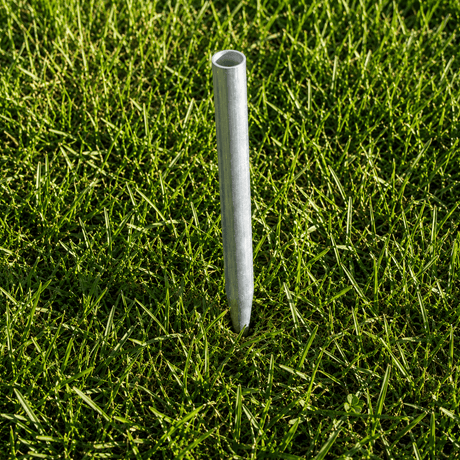 Metal pipe standing upright in green grass