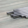 A collection of aluminium tubes laid out on a wooden surface, used for making garden cages.