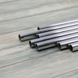A collection of aluminium tubes laid out on a wooden surface, used for making garden cages.