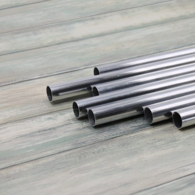 A collection of aluminium tubes laid out on a wooden surface, used for making garden cages.