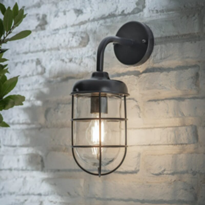 Black barn light hanging on brick wall with light on