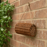 bee hotel hanging on a brick wall with plants nearby
