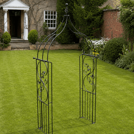 Decorative garden arch on a grassy lawn with a house in the background