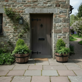 Wooden half barrel plants by stone house doorway entrance