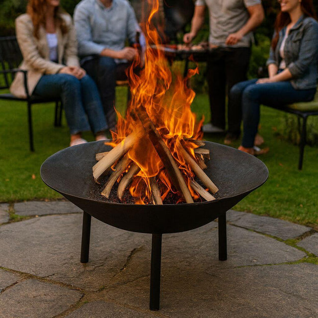 cast iron fire pit burning logs on a garden patio with people gathered around