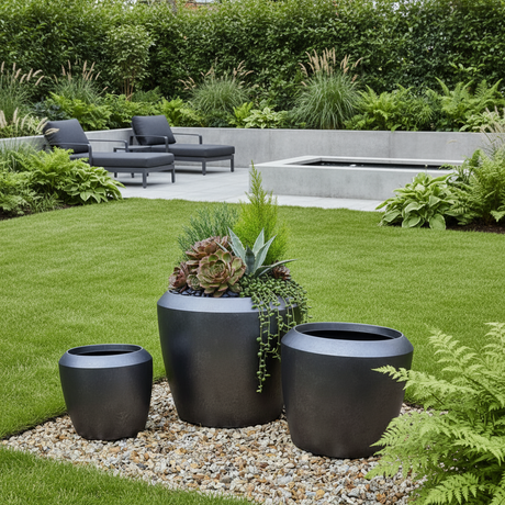 Modern garden with black planters, green grass, and a fire pit.