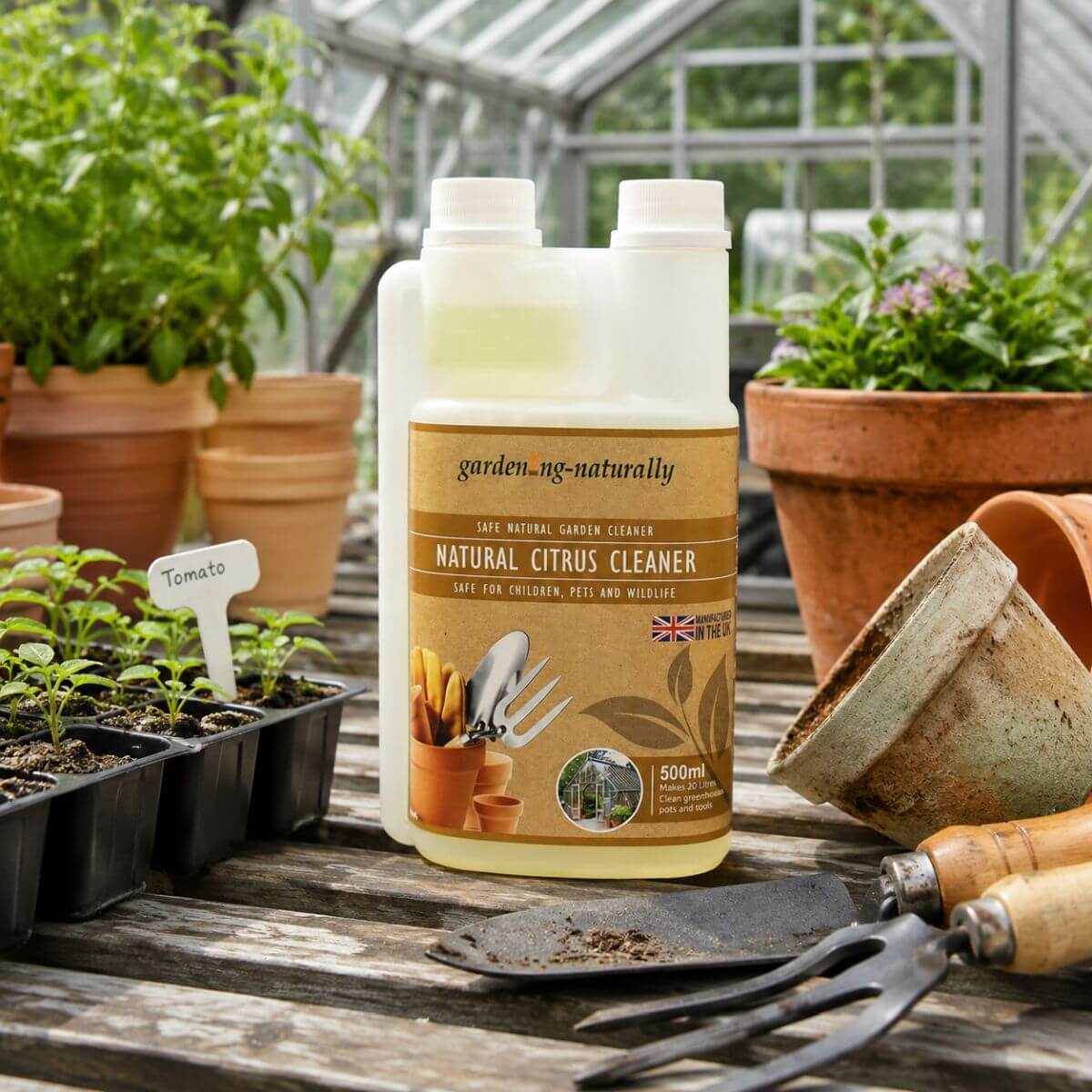 Natural Citrus Cleaner bottle on a garden workbench with plants and gardening tools.