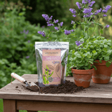 Compost pellets packaging with potted plants on a wooden table outdoors