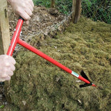 A person using a red compost aerator tool to turn compost. 