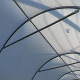 Close-up of a transparent greenhouse with metal frames against a blue sky.