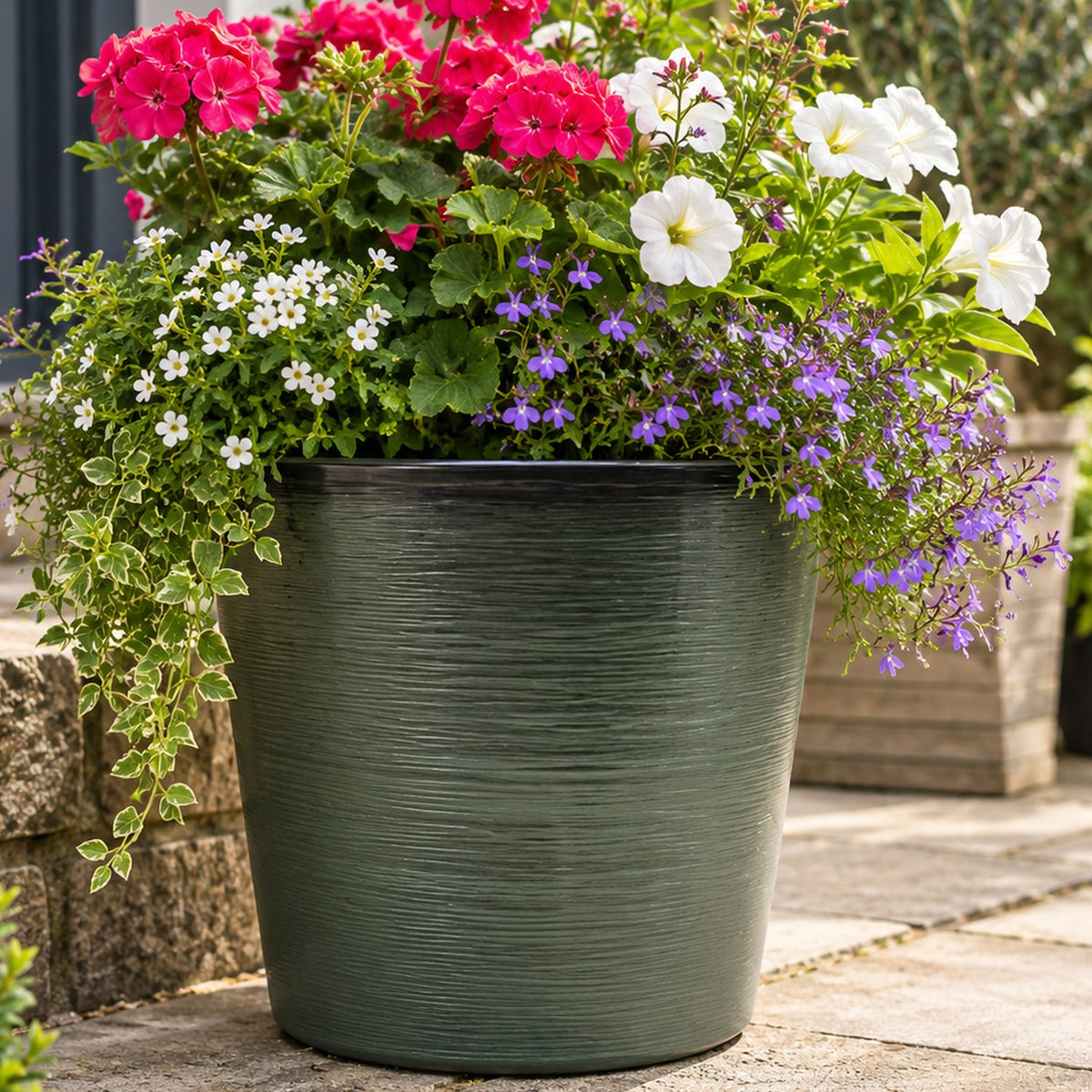Deep green planter outside with flowers