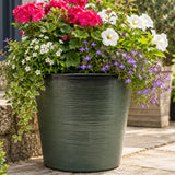 Deep green planter outside with flowers
