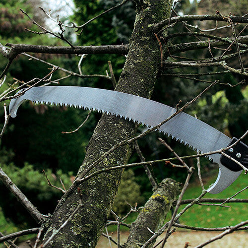 Pruning saw cutting through a tree branch with a blurred natural background