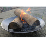 A fire bowl with two logs on it, producing flames and smoke, placed on a stone surface.
