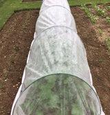 A garden with flexible tunnels covered in white netting, designed to protect plants.