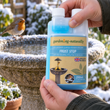 Gardening Naturally Frost Stop 250ml with built-in measuring chamber beside a bird bath and robin in a frosty winter garden.