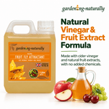 A 1 litre plastic jug of gardening naturally Fruit Fly Attractant filled with amber liquid, shown beside a small glass bottle of the same liquid and fruit imagery including an apple, cherry, and grapes. 