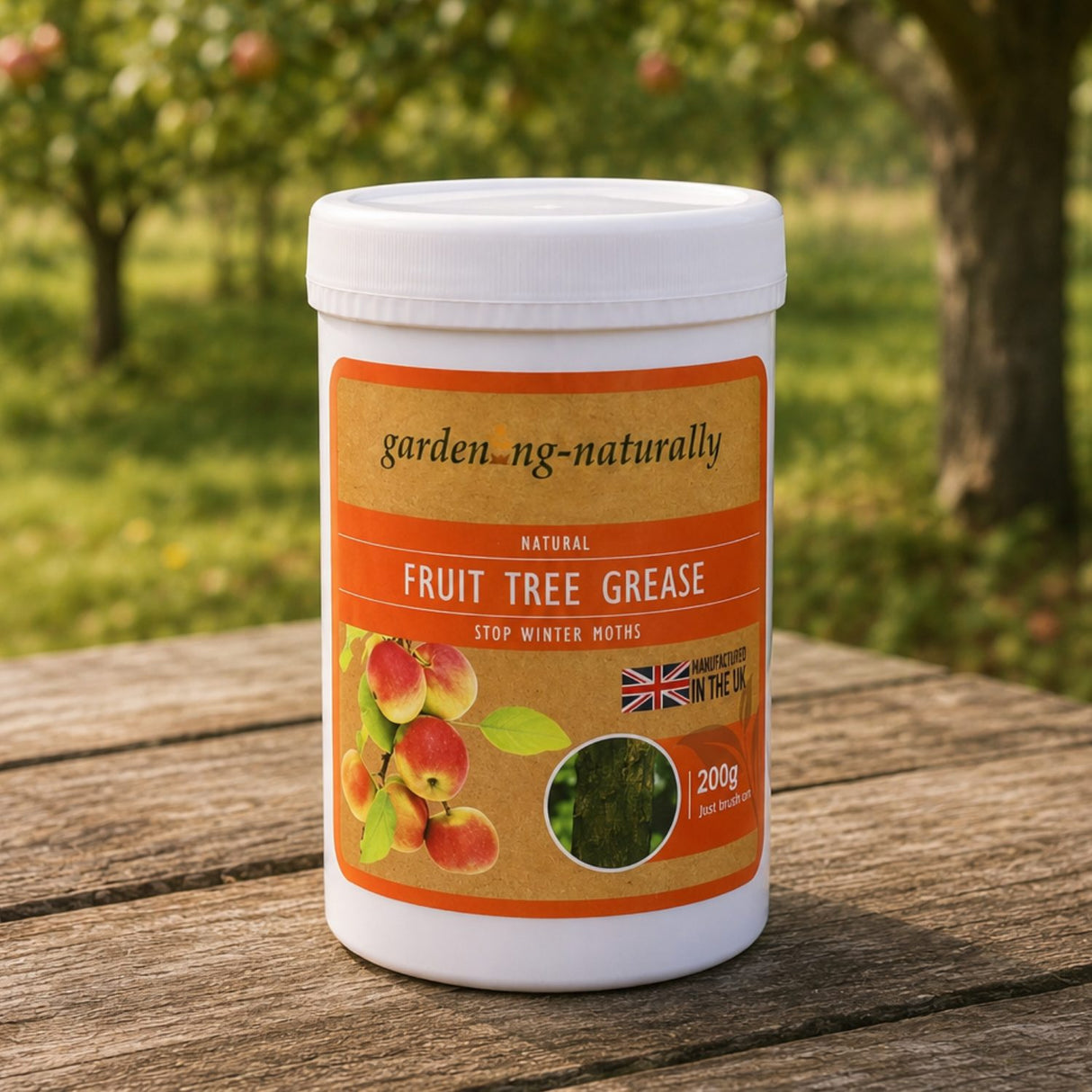 A white plastic tub of gardening naturally Fruit Tree Grease sits on a weathered wooden table with a blurred garden background.
