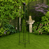 Black metal garden obelisk with decorative top in a garden setting