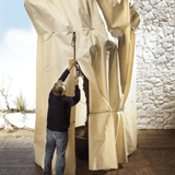 man covering huge plant with frost protection bag