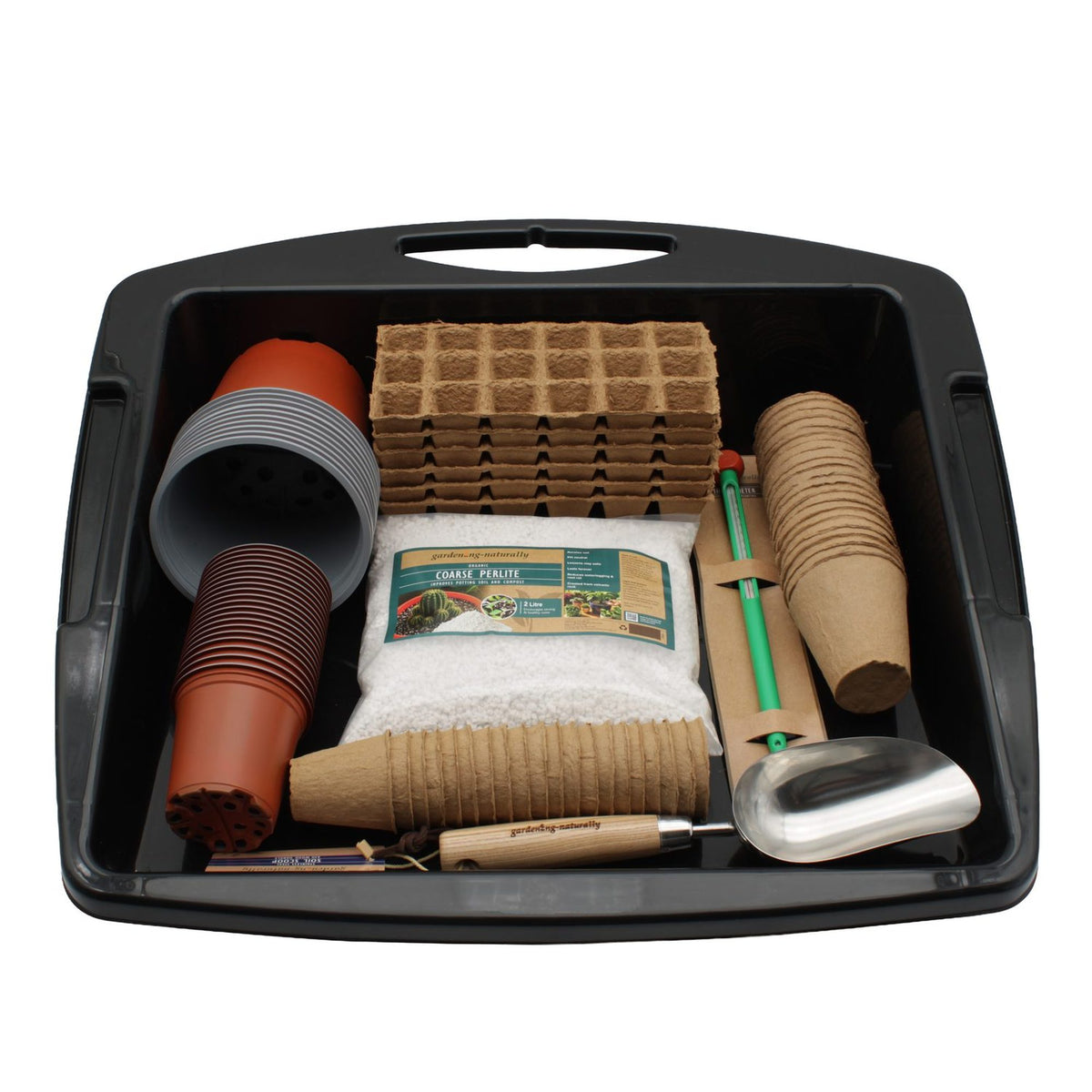 A gardening starter kit arranged inside a black plastic tray, including seed starter packs, pots, grow bags, seedling towers, a hand trowel, and a metal scoop, photographed on a white background.