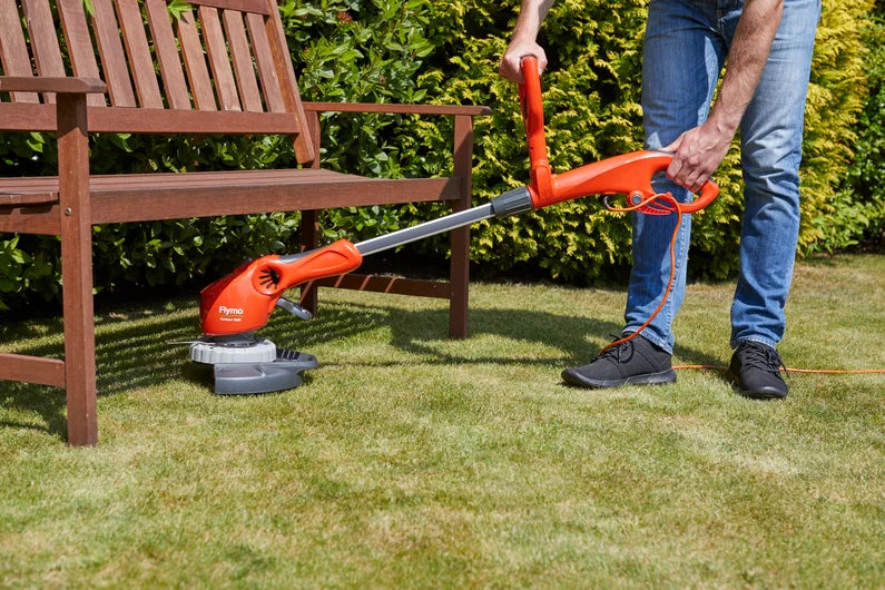 Grass Ssrimmer in use in garden under bench