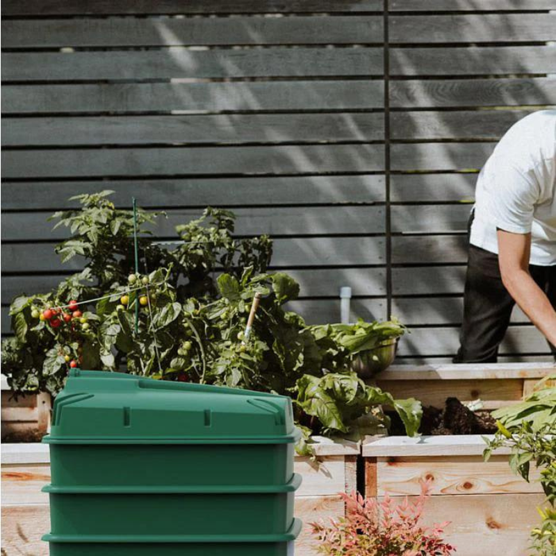 Green 3 tray wormery in a garden with vegetables and raised bed