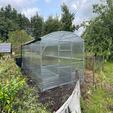greenhouse on grass area with metal fence surrounding