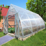 A large pointed greenhouse with doors open and plants inside