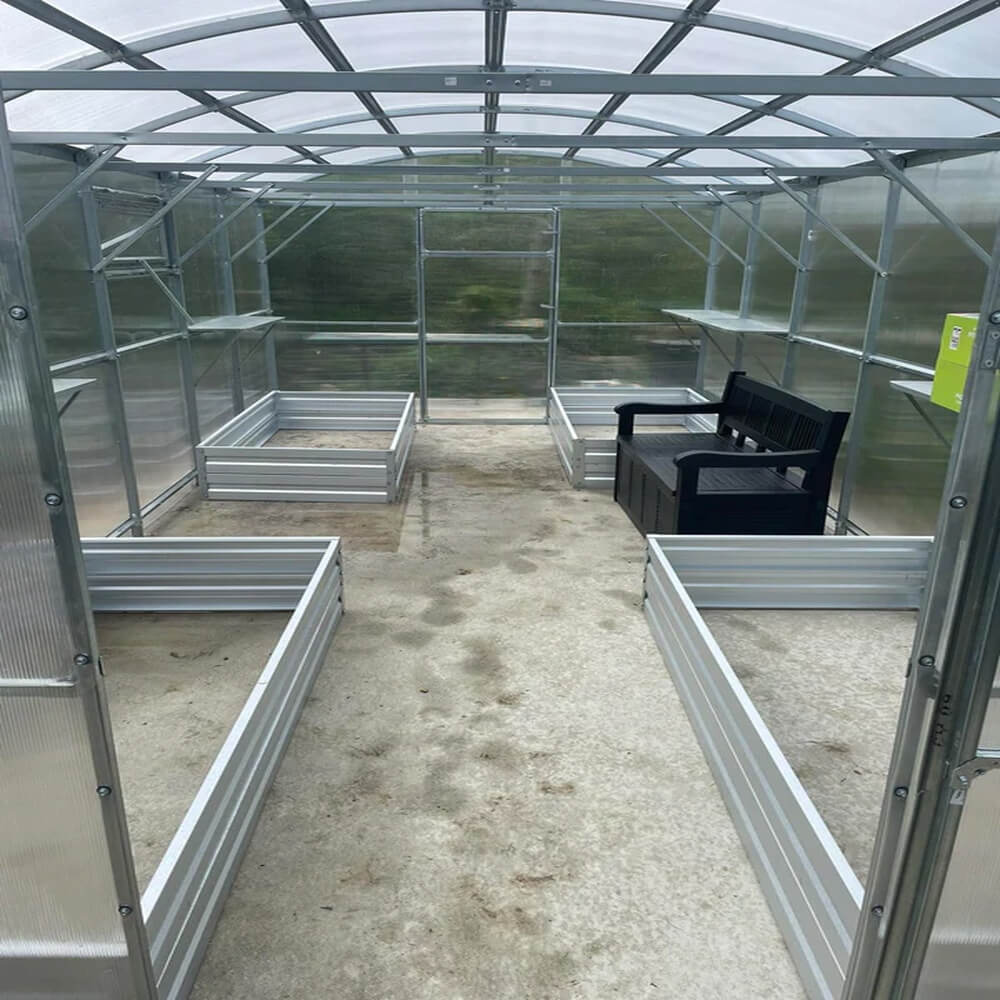 inside of a greenhouse with a bench and metal raised beds