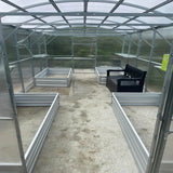 inside of a greenhouse with a bench and metal raised beds
