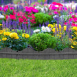 A dark grey, curved garden border made of rubber material, installed around a bed of colorful flowers.