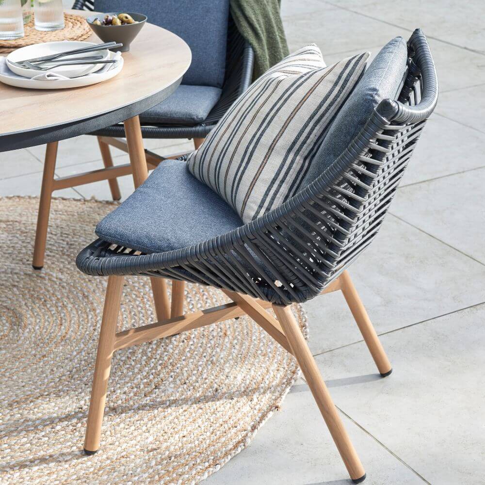 Outdoor grey and wood wicker chair with cushions on patio