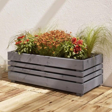 Grey wooden planter box with plants on a wooden deck