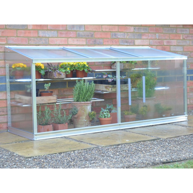 A small half-wall cold frame made of aluminum with reinforced safety glass, containing various potted plants.