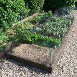 A garden with flexible tunnels covered in white netting, designed to protect plants.